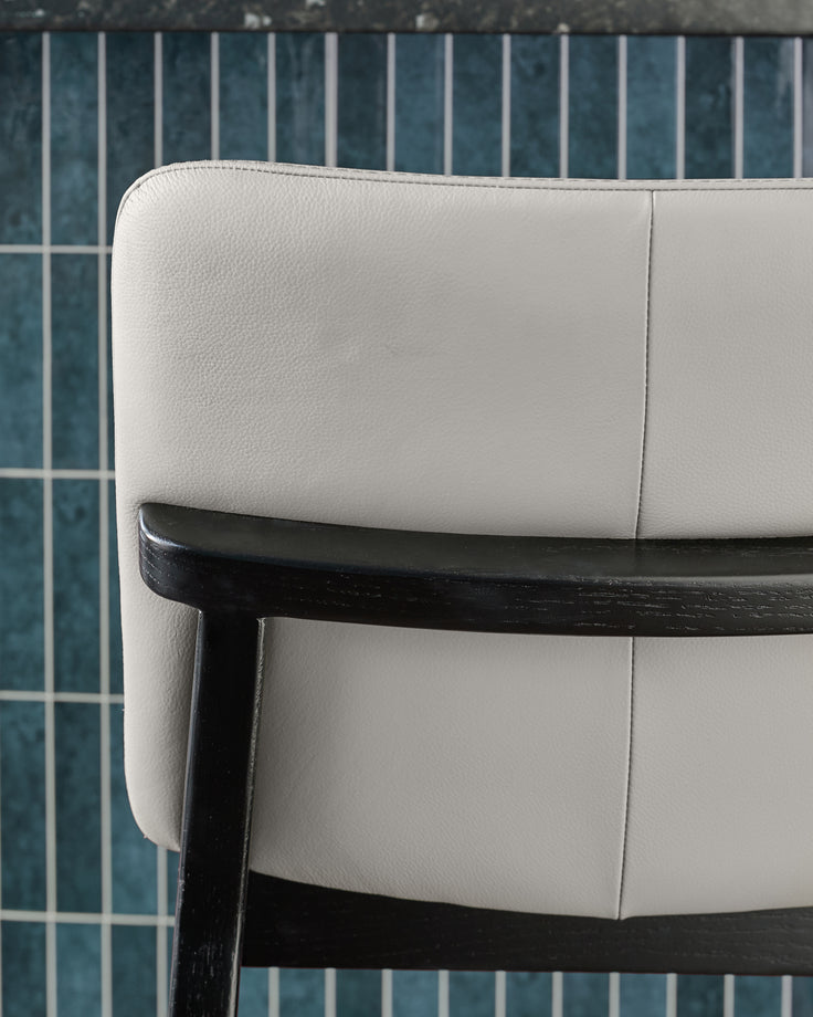 Otis bar stool in light grey leather with black wooden frame, shown in side angle detail view.