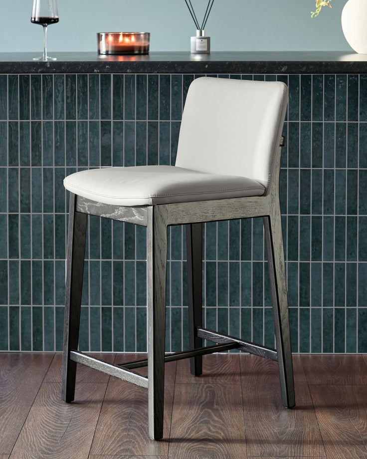 Otis bar stool with light grey leather seat and backrest, weathered grey wood frame, and black footrest.