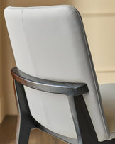 Otis dining chair in light grey leather, shown from rear angle with dark wood frame visible.