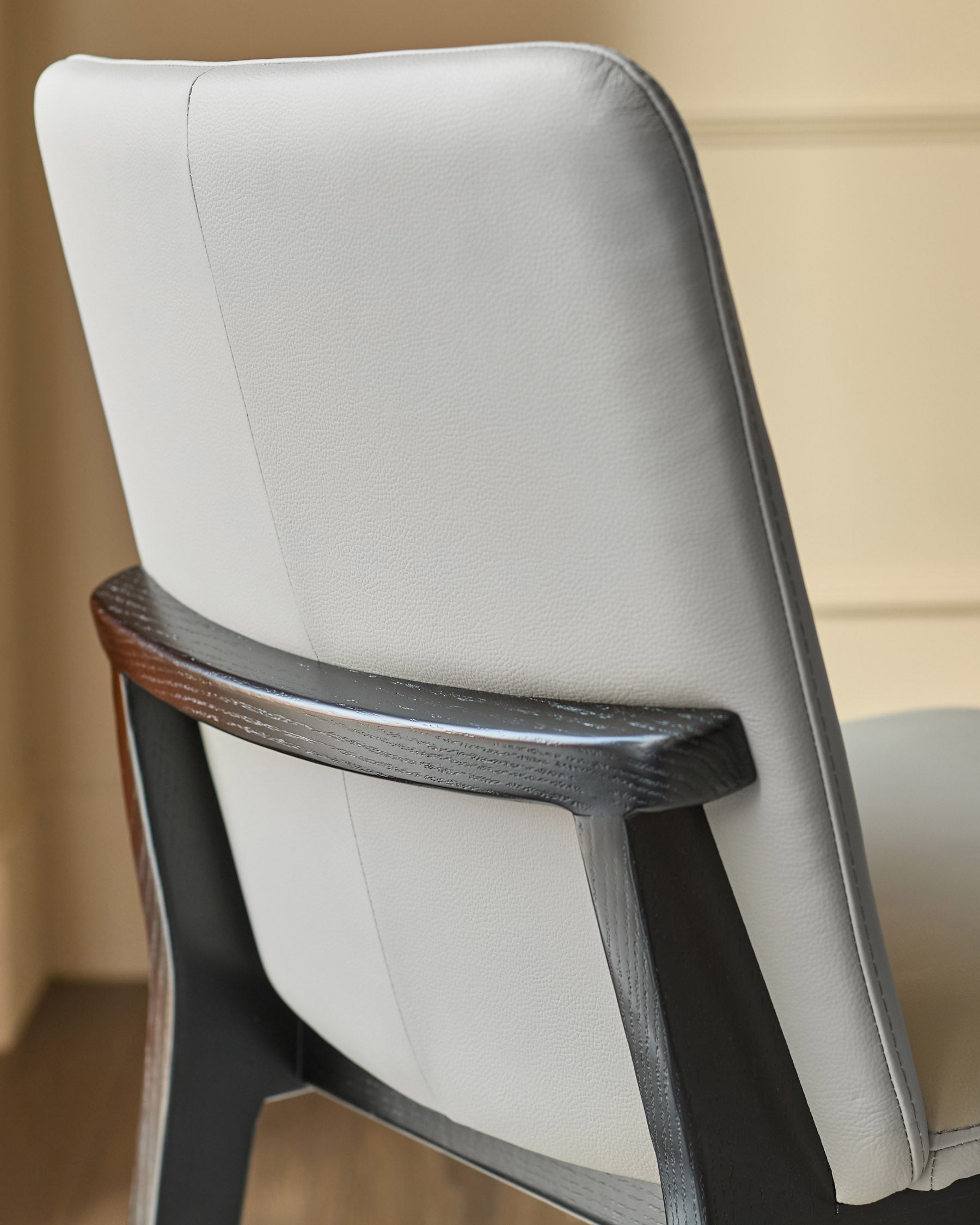 Otis dining chair in light grey leather, shown from rear angle with dark wood frame visible.