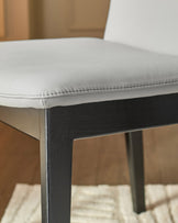 Otis dining chair in light grey leather with dark wood legs, shown from side angle detail.