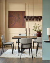Otis dining chair in light grey leather, shown in modern dining room setting with dark wood table and contemporary pendant lighting.