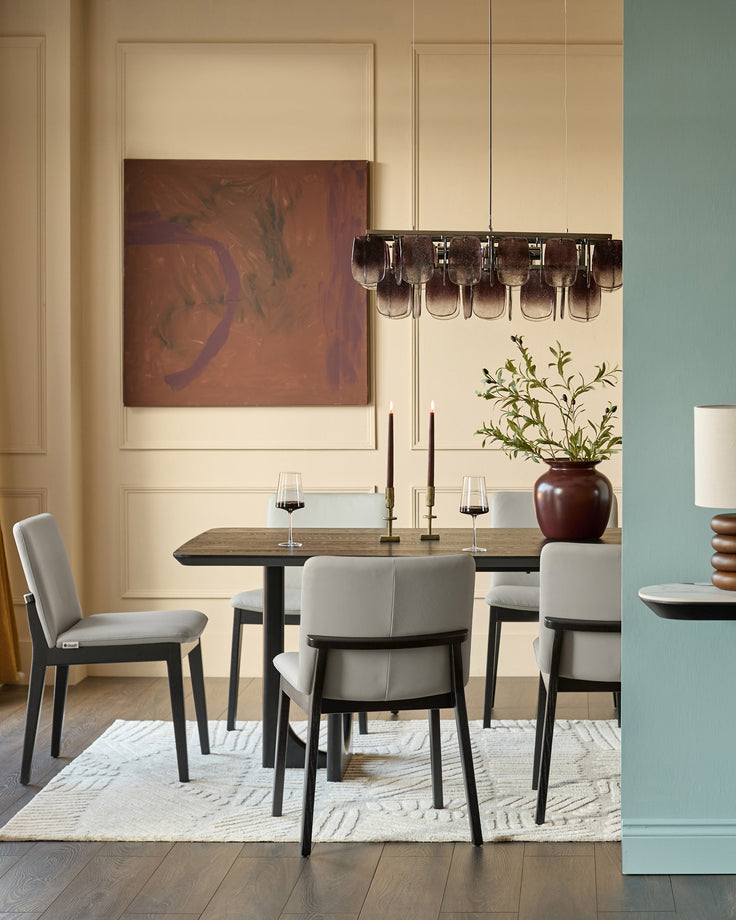 Otis dining chair in light grey leather, shown in modern dining room setting with dark wood table and contemporary pendant lighting.