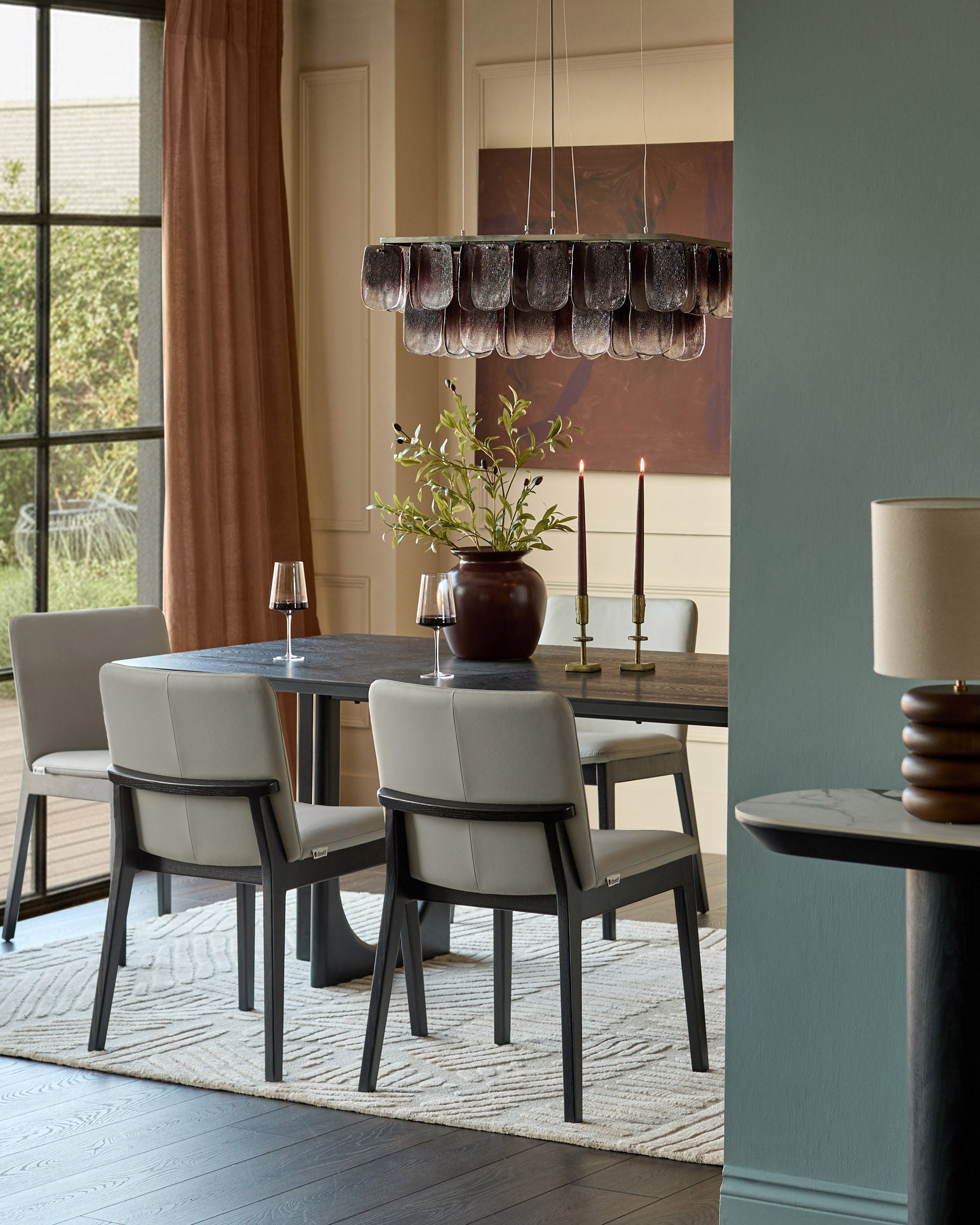 Otis dining chair in light grey leather, black wooden frame, shown at dining table in modern interior setting.