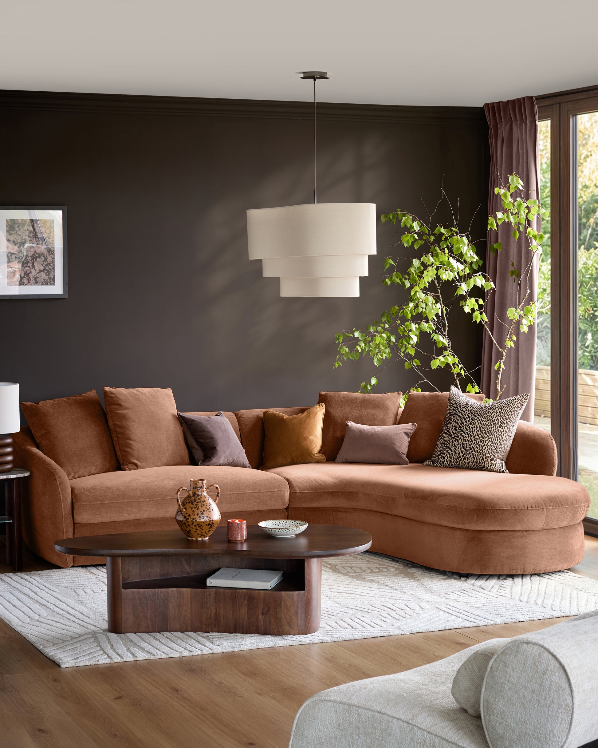 Ottilie right-hand corner chaise sofa in apricot fabric, styled in a modern living room with dark walls and decorative pillows.