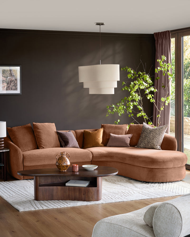 Ottilie right-hand corner chaise sofa in apricot fabric, styled in a modern living room with dark walls and decorative pillows.