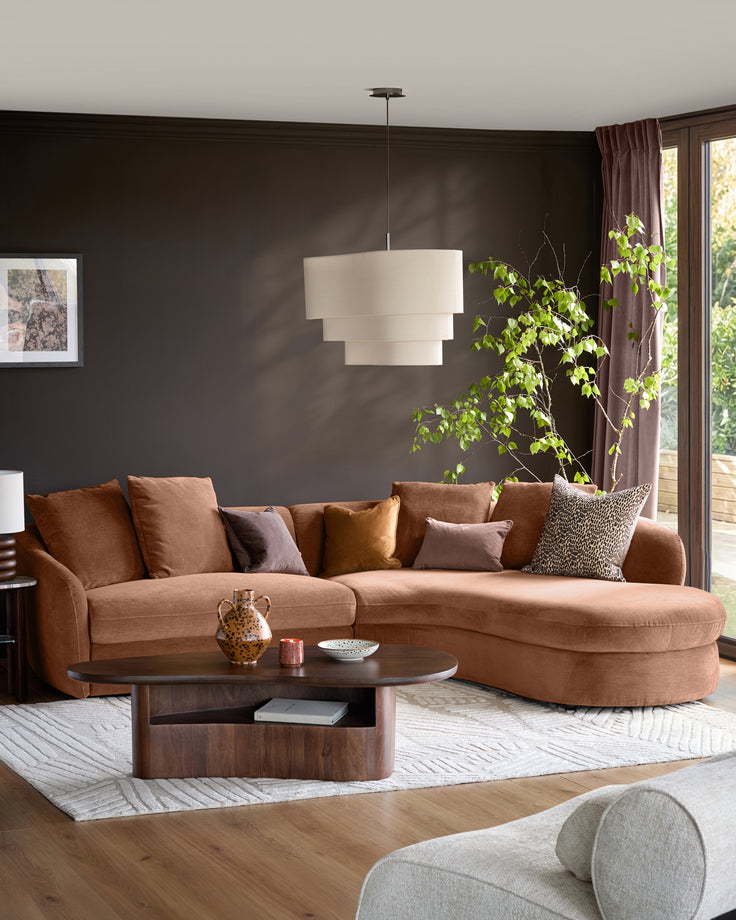 Ottilie right-hand corner chaise sofa in apricot fabric, styled in a modern living room with dark walls and decorative pillows.