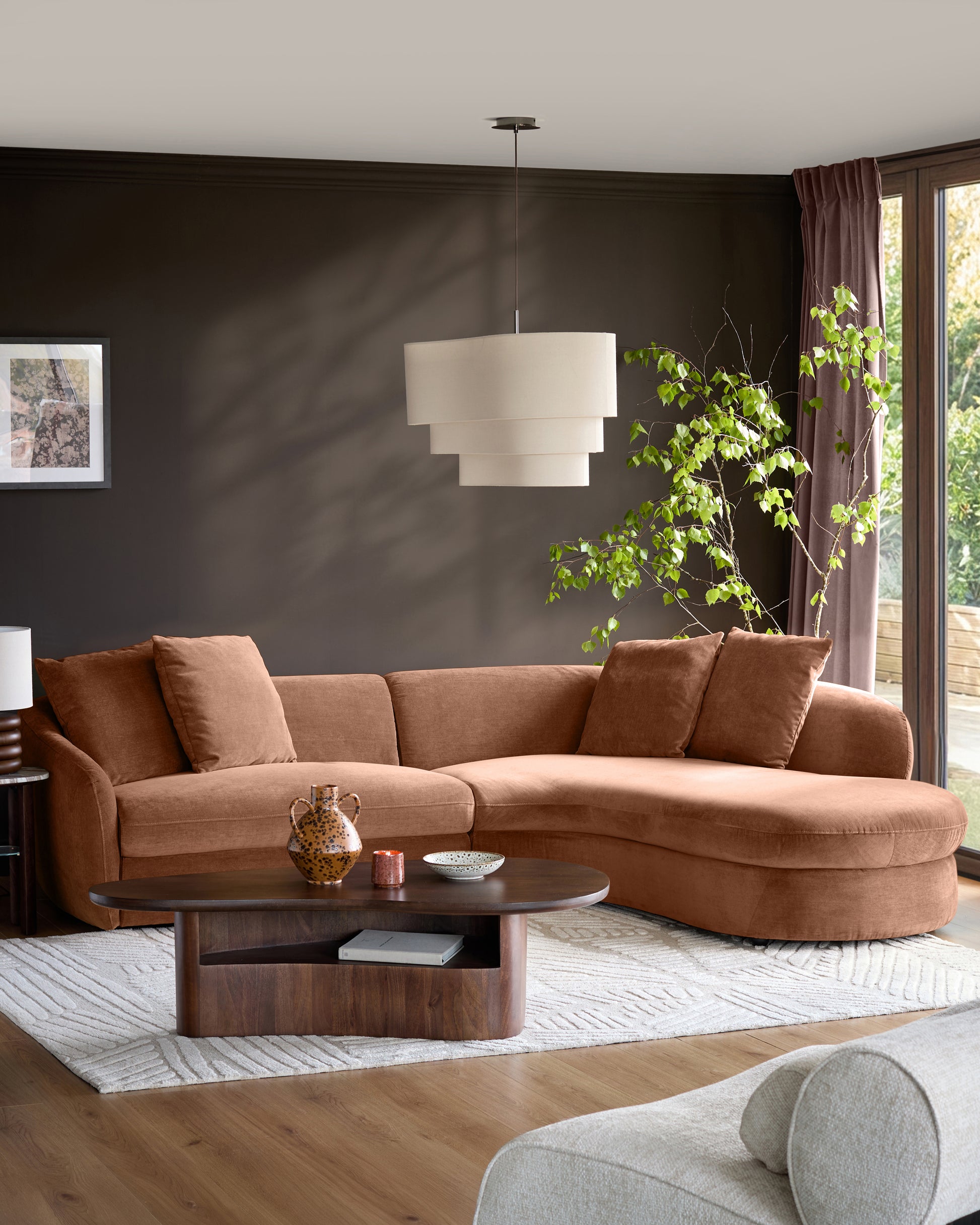 Apricot fabric right-hand corner chaise sofa in a modern living room with dark walls and wooden coffee table.