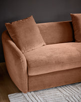 Apricot fabric right-hand corner chaise sofa with curved armrests and matching cushions, angled view against gray wall.