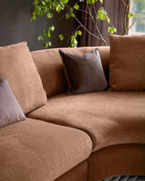 Ottilie right-hand corner chaise sofa in apricot fabric with dark brown scatter cushions, angled view.