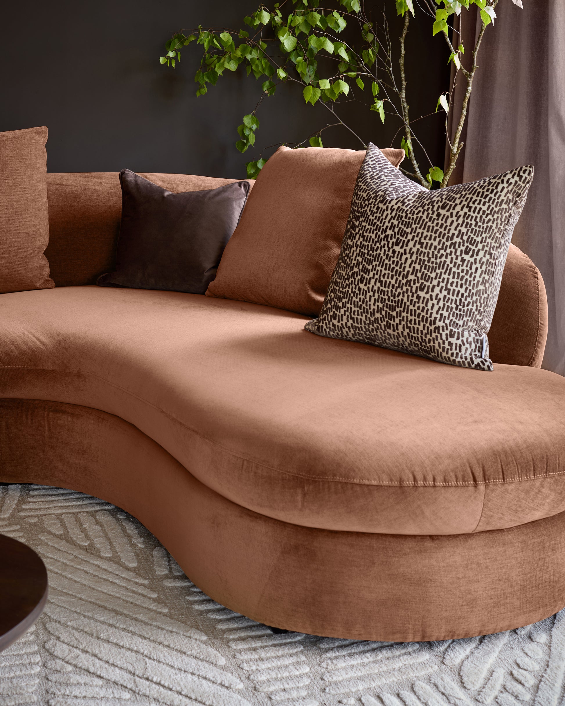 Ottilie right-hand corner chaise sofa in apricot fabric, styled with decorative pillows and trailing foliage plant.