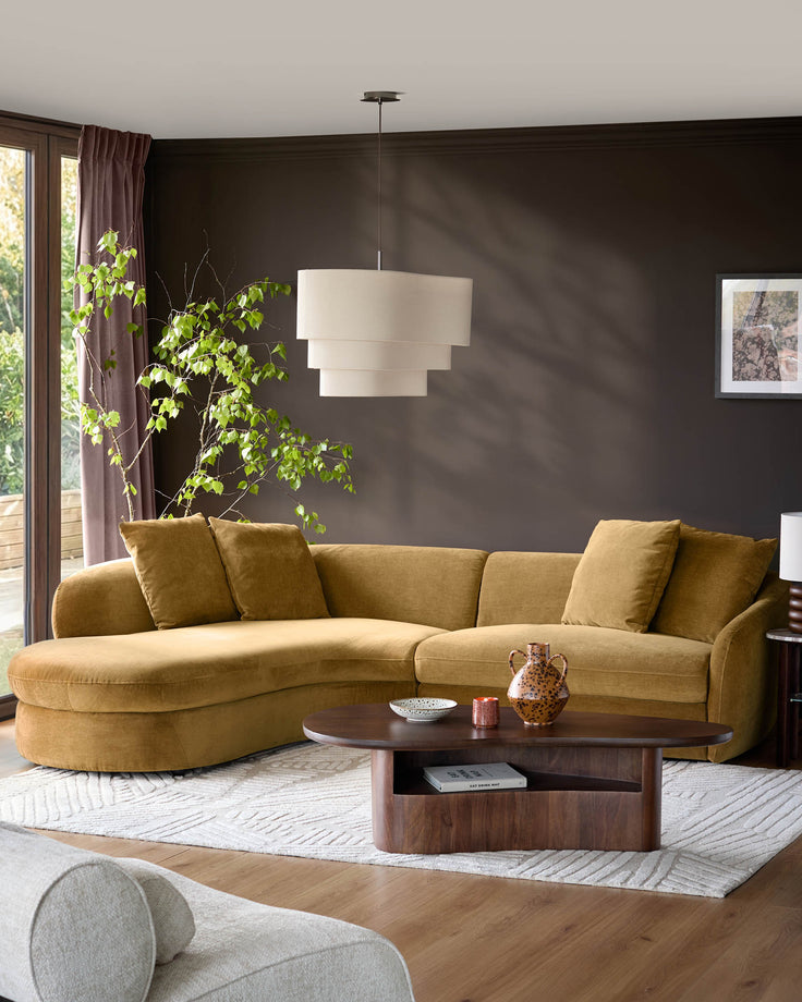 Ochre fabric left-hand corner chaise sofa in a modern living room with dark walls and wooden coffee table.