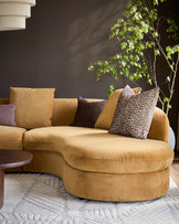 Ochre fabric right-hand corner chaise sofa with curved design and decorative pillows in a styled living room setting.