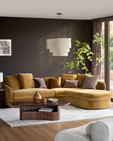 Ochre right-hand corner chaise sofa with curved design, shown in a modern living room setting with dark walls and styled with accent pillows.