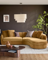 Ochre fabric right-hand corner chaise sofa with curved design and decorative cushions in a dark modern living room.