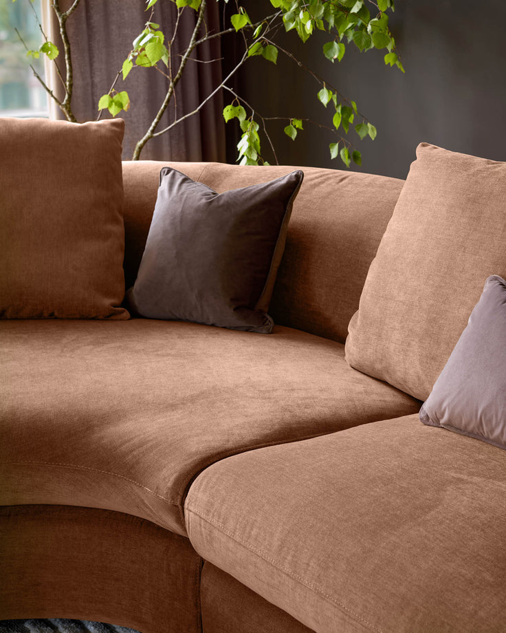 Ottilie left-hand corner chaise sofa in apricot fabric with grey scatter cushions, styled with trailing ivy plant overhead.