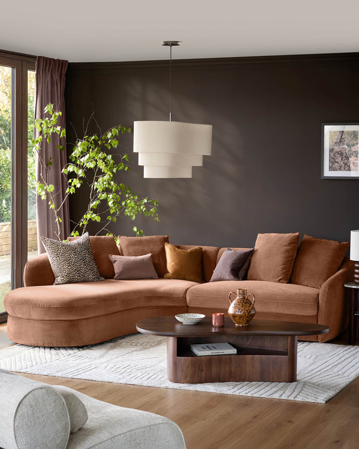 Ottilie left-hand corner chaise sofa in apricot fabric, displayed in a modern living room with dark walls and styled with decorative pillows.