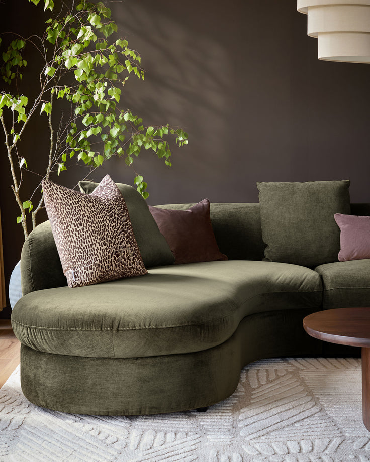 Ottilie left-hand corner chaise sofa in olive green fabric, styled with decorative pillows in a modern living room setting.