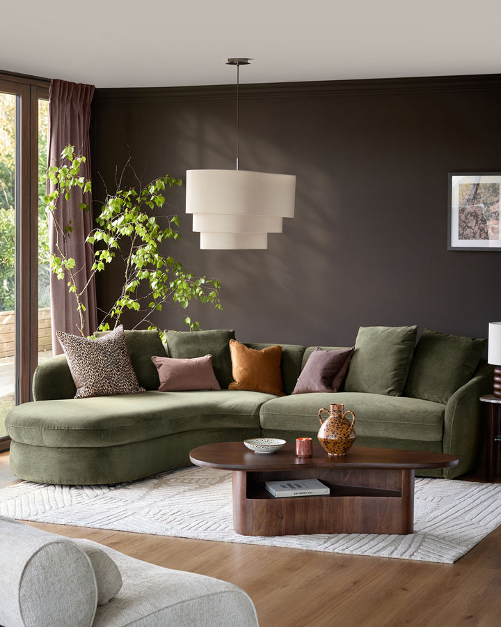 Olive green left-hand corner chaise sofa with curved arms in a modern living room setting.
