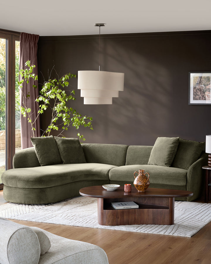Olive green fabric left-hand corner chaise sofa in a modern living room with dark walls and wooden coffee table.
