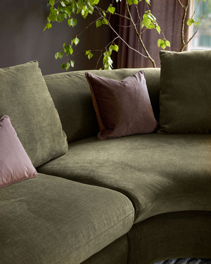 Olive green right-hand corner chaise sofa with decorative cushions in a styled living room setting.