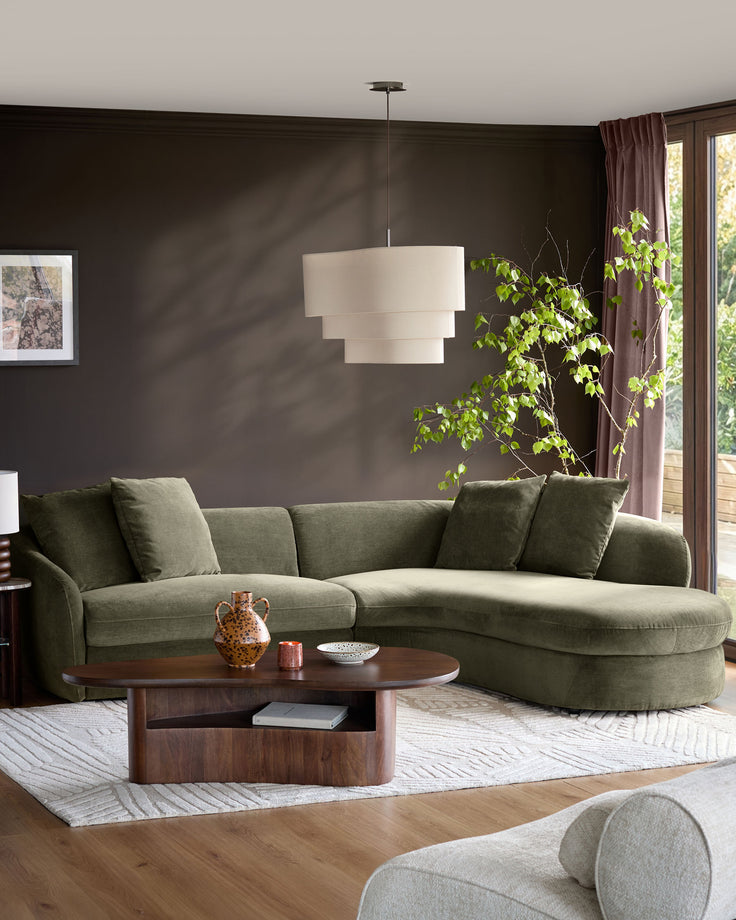 Ottilie right-hand corner chaise sofa in olive green fabric, displayed in a modern living room setting with dark walls.