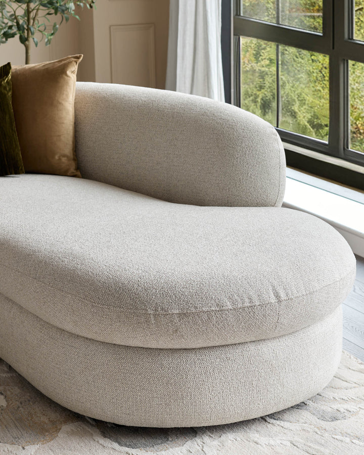 Cream fabric right-hand corner chaise sofa with curved design, positioned by large windows with natural light.