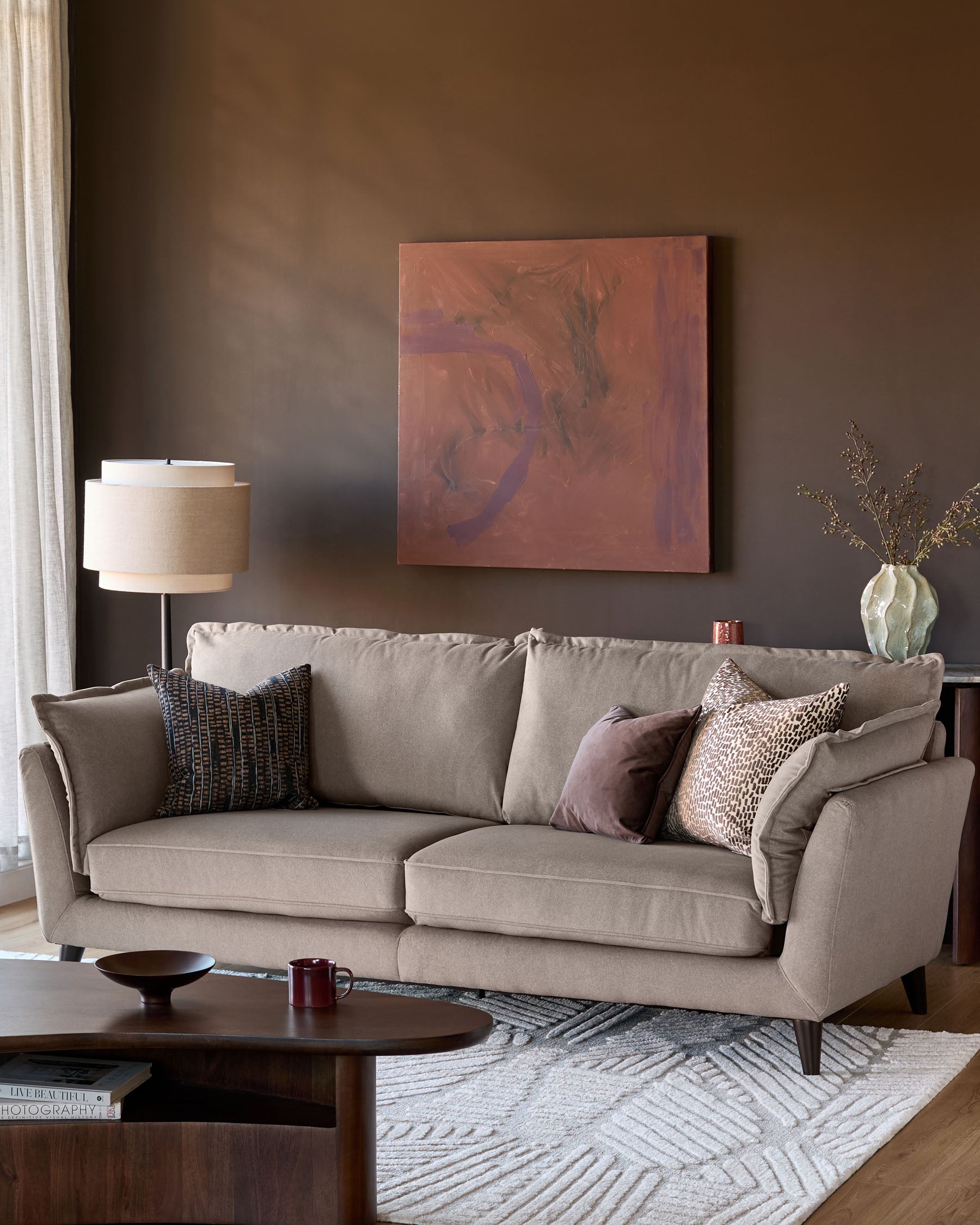 Otto 3-seater sofa in mocha fabric, displayed in a styled living room setting with decorative pillows and wooden legs.