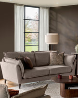 Otto 3-seater sofa in mocha fabric, shown in a living room setting with decorative pillows and wooden legs.