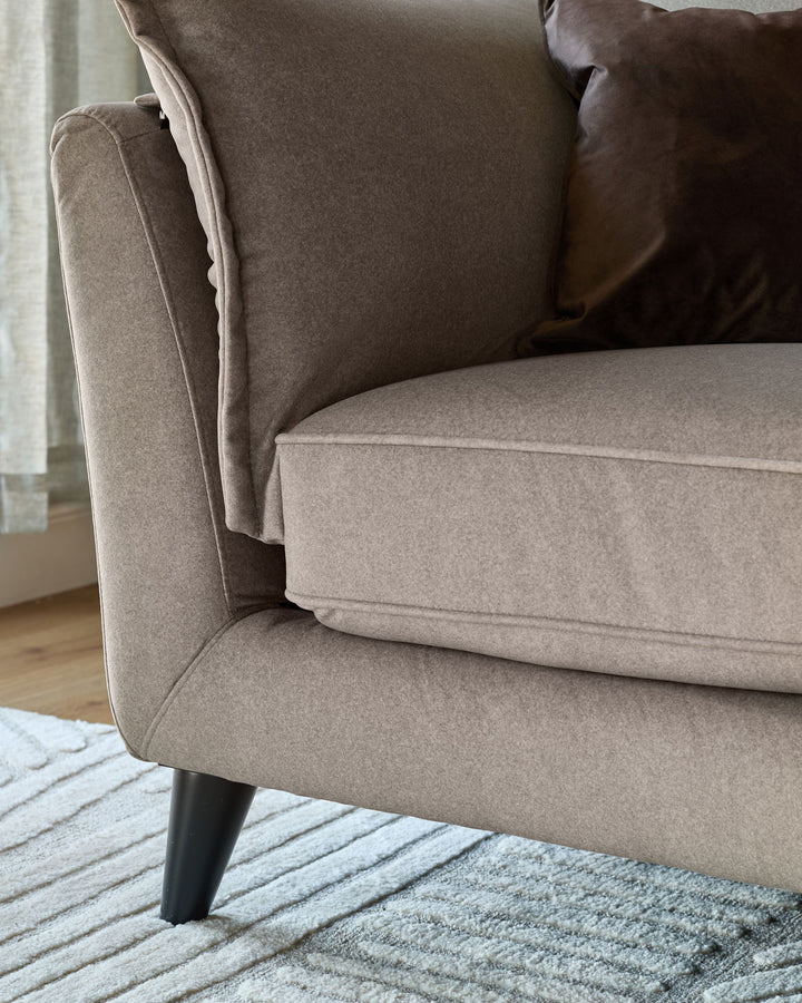 Otto 3-seater sofa in mocha fabric, side view showing cushioned seat, back pillow, and dark tapered legs on striped rug.