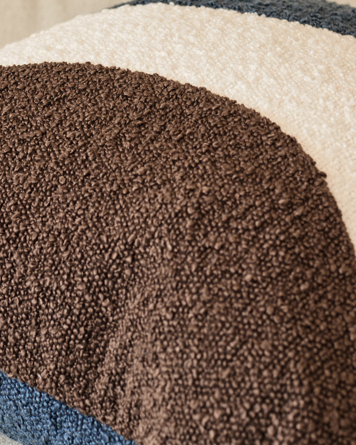 Close-up of Harmony Cushion showing layered fabric textures in navy, brown, cream, and charcoal colors.