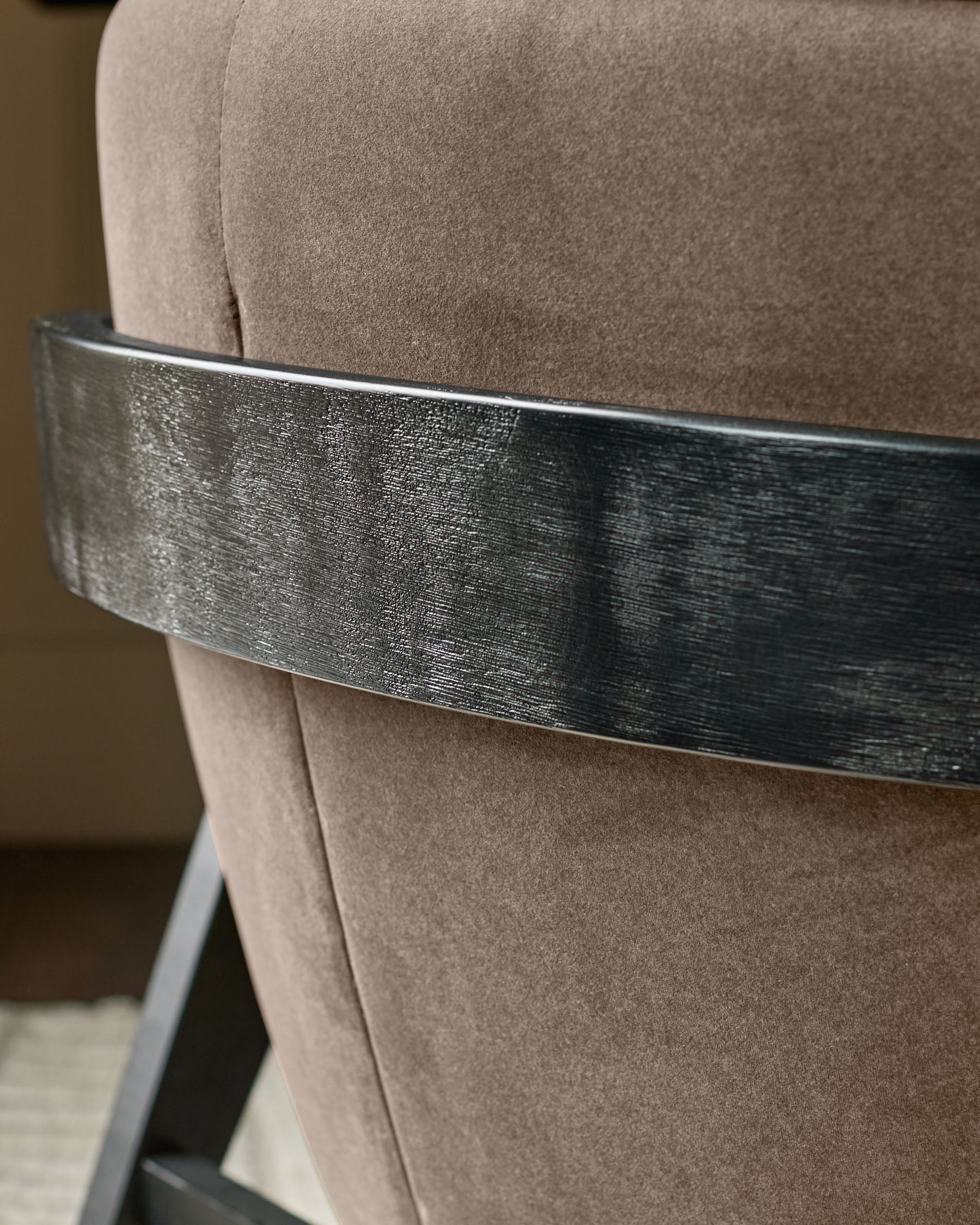 Mocha fabric chair with brushed metal band accent wrapped around the back.