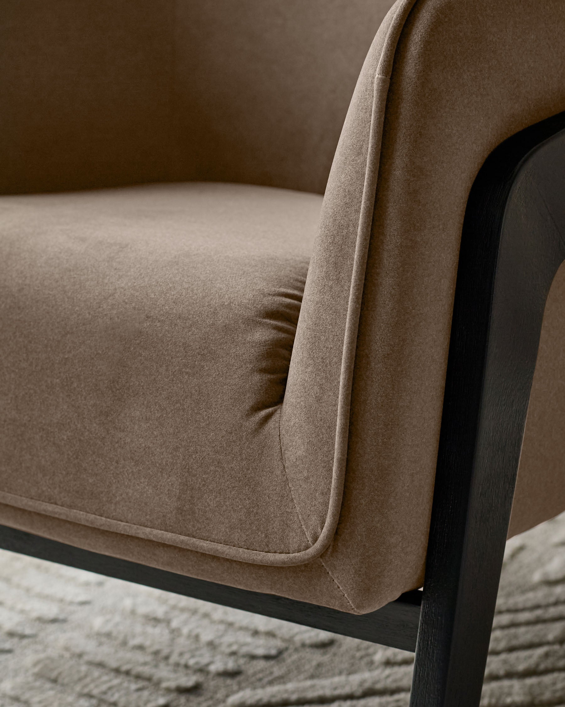Palmer Occasional Chair in mocha fabric with black wooden legs, shown from side angle detail.