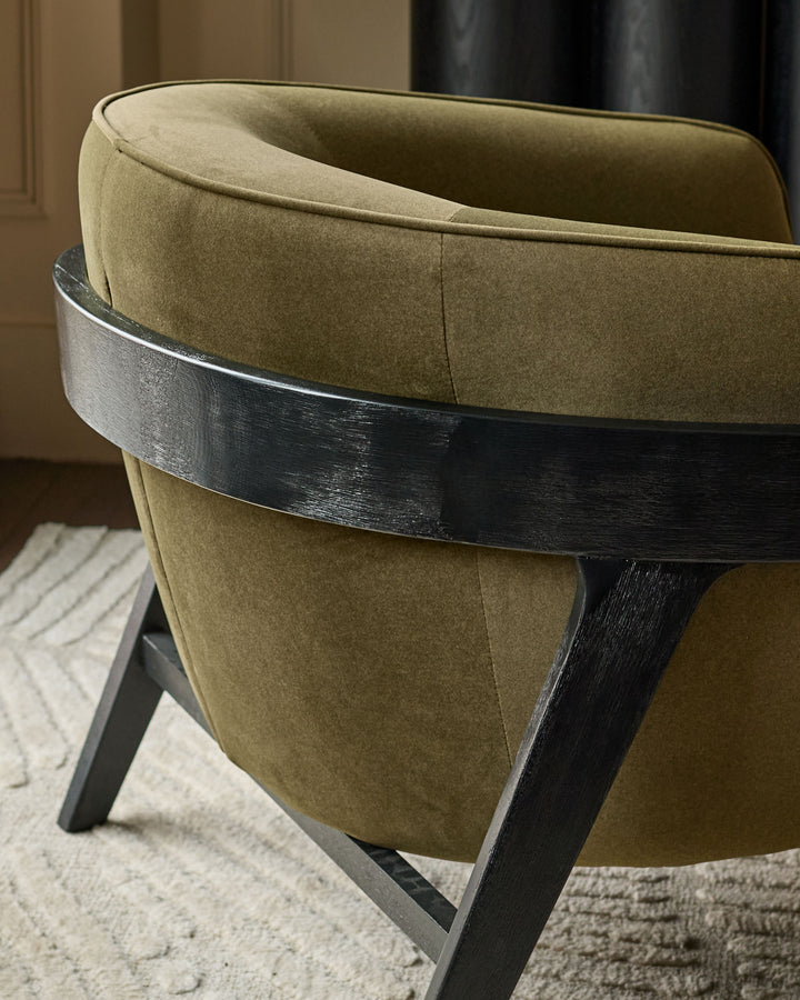Palmer occasional chair in pistachio green fabric with black wood frame, shown from rear angle on neutral rug.