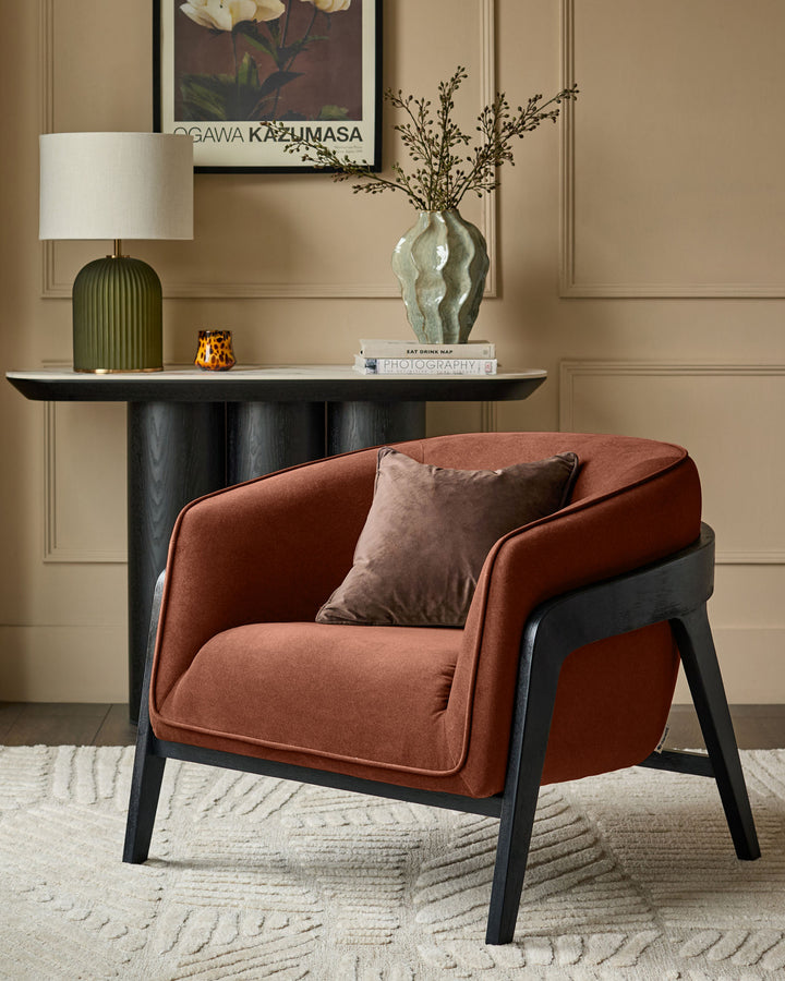 Palmer occasional chair in toffee-red fabric with black wooden legs, styled in a living room setting with console table and accessories.