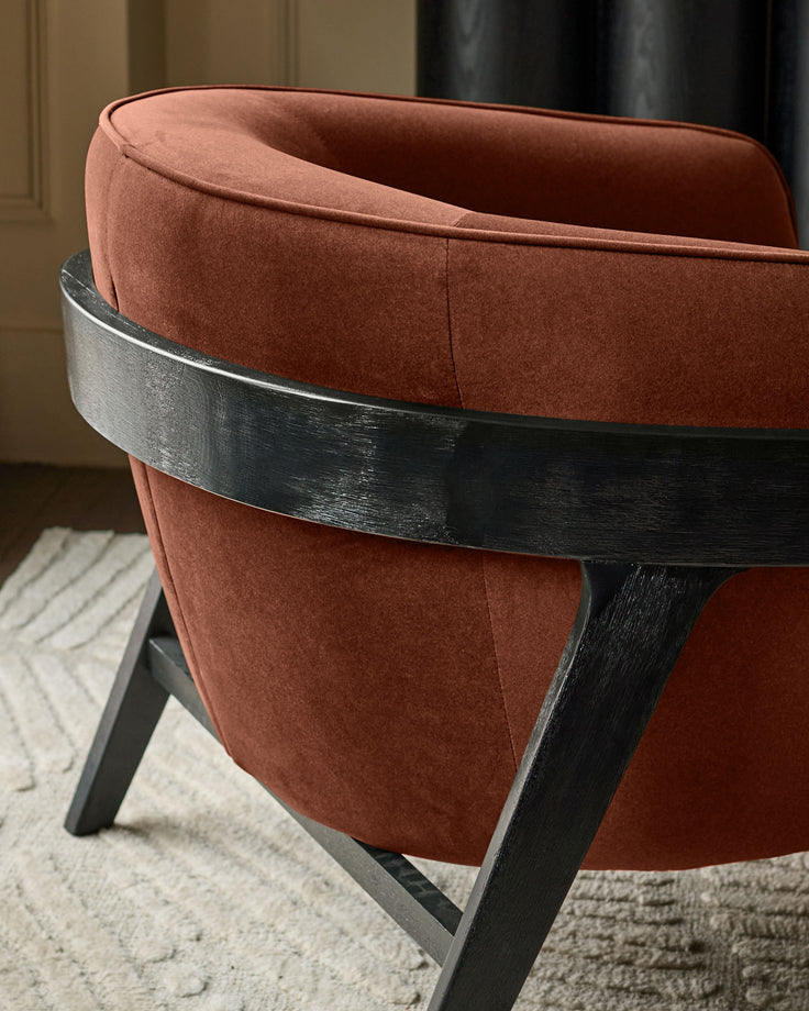 Palmer occasional chair in toffee red fabric with black wooden frame, shown at an angle displaying the curved backrest and legs.