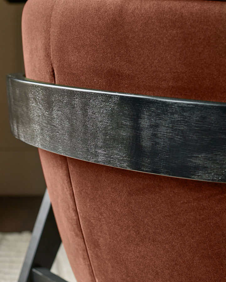 Palmer occasional chair in toffee-red fabric with brushed metal band detail, close-up side view.