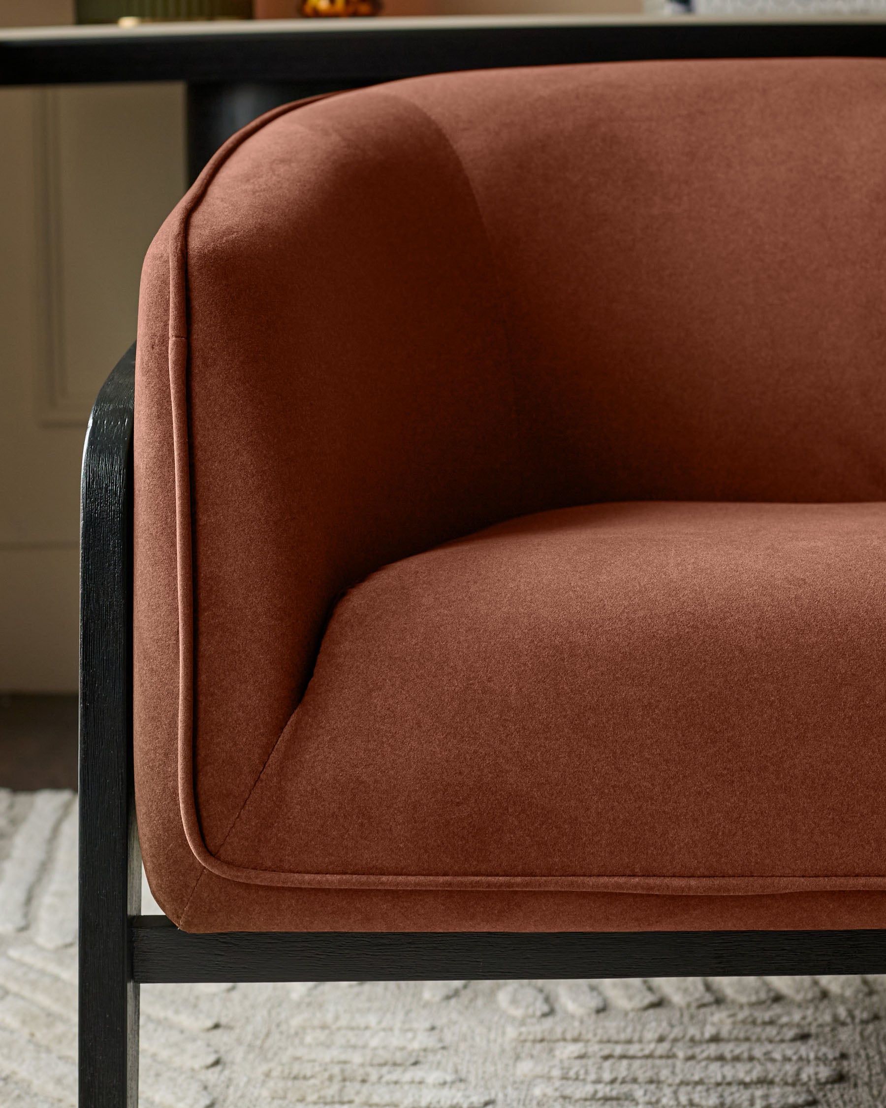 Palmer Occasional Chair in toffee-red fabric with curved backrest and black wooden frame, side view detail.