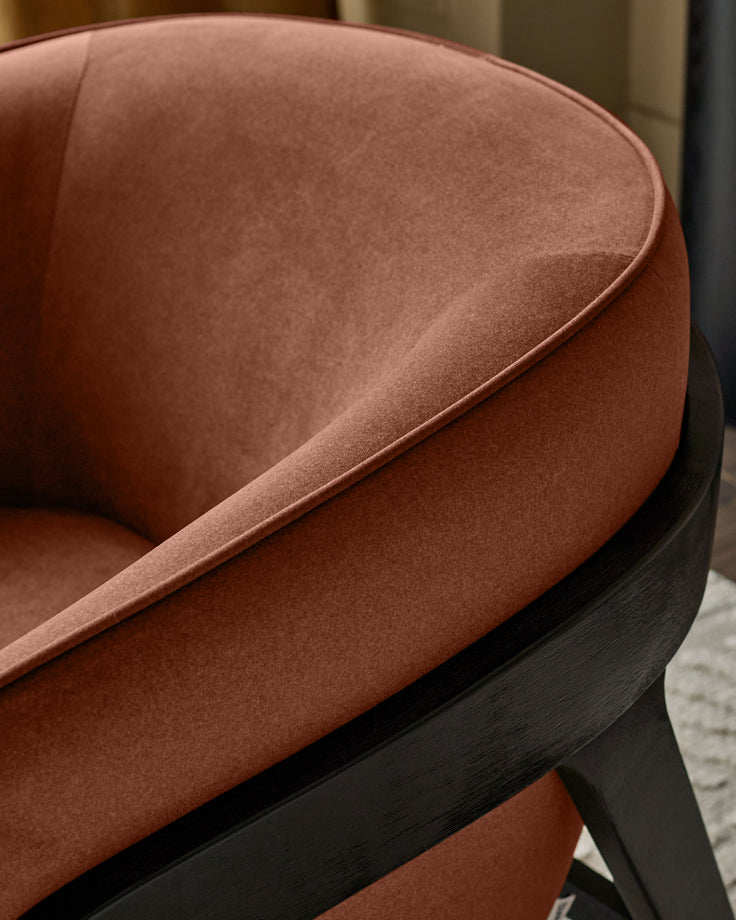 Palmer Occasional Chair in toffee-red fabric with black wooden frame, shown from a close-up side angle.