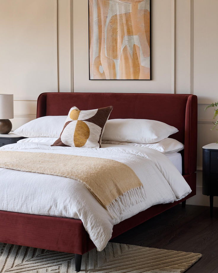 Stylish bedroom featuring a red upholstered bed, white linens and a contemporary art piece, creating a cosy and modern aesthetic.
