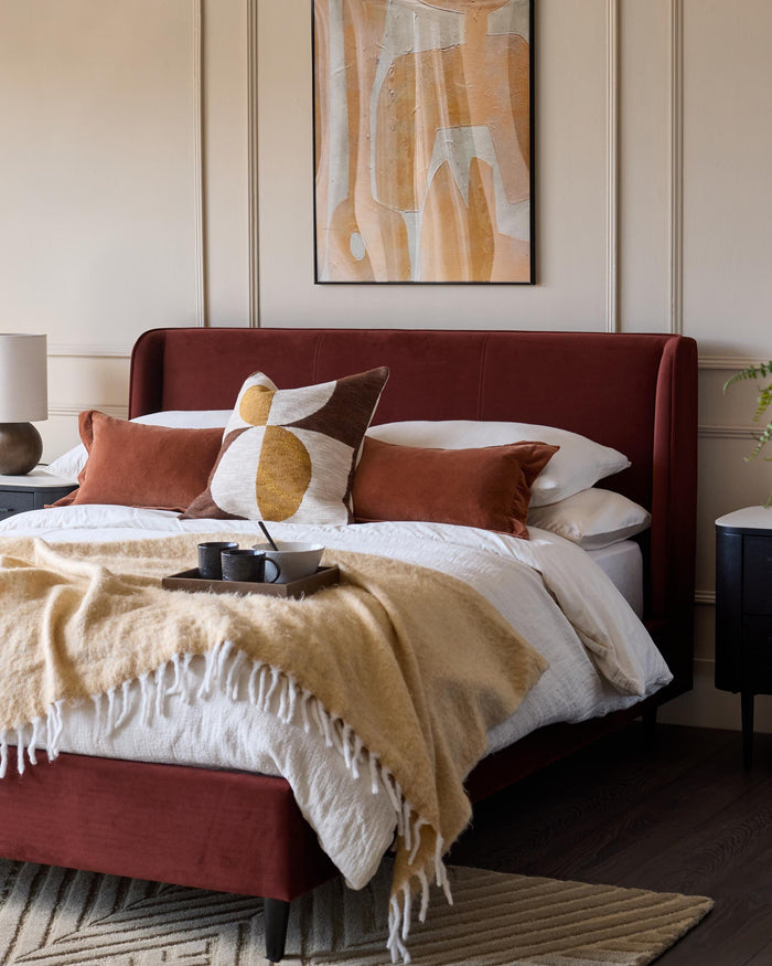 Bedroom features a red velvet bed frame, abstract artwork, and bedside tables. A cosy, modern design.