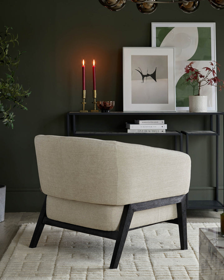 Stylish armchair with dark wood frame, complemented by a console table and framed art, adding a modern touch to any living space.