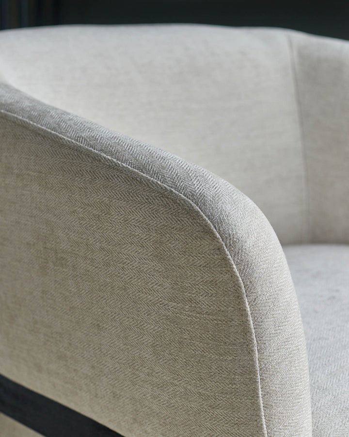 Close-up of a stylish, light-coloured armchair with a textured fabric finish, perfect for a modern living space.