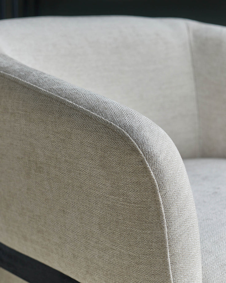 Close-up of a stylish, light-coloured armchair with a textured fabric finish, perfect for a modern living space.