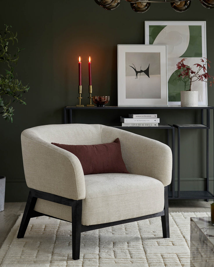 Stylish interior with a cream armchair, dark wood frame and a plum cushion against a deep green wall.