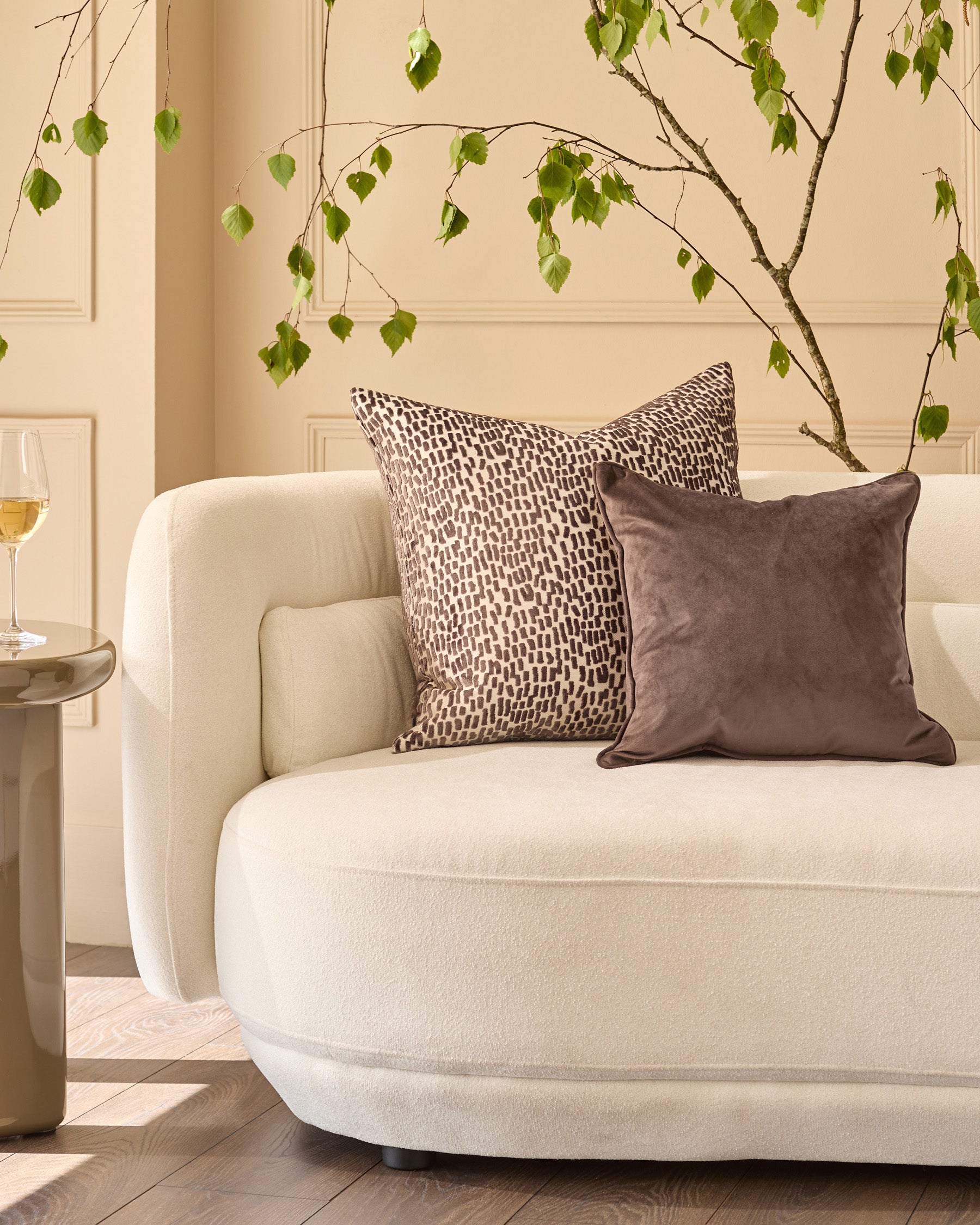 Payton Large Chocolate Cushion displayed on a cream armchair in a styled living room setting.