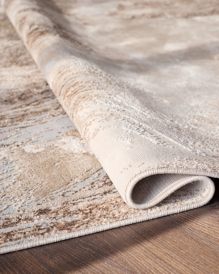 Perla Expression medium textured rug in silver, rolled and displayed on wooden flooring showing texture detail.