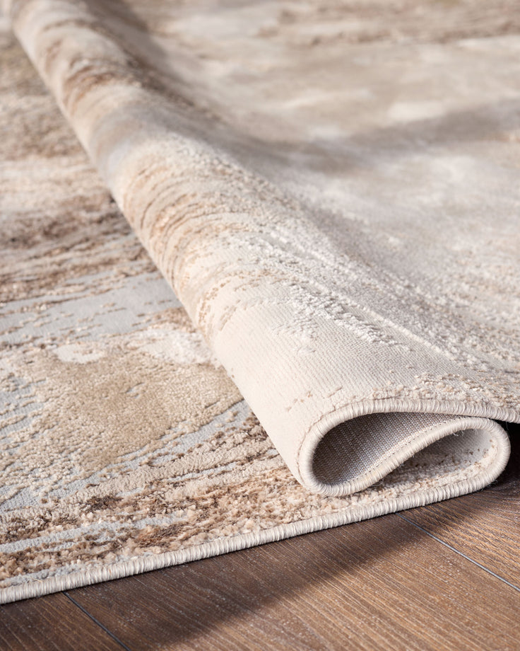 Perla Expression medium textured rug in silver, rolled and displayed on wooden flooring showing texture detail.