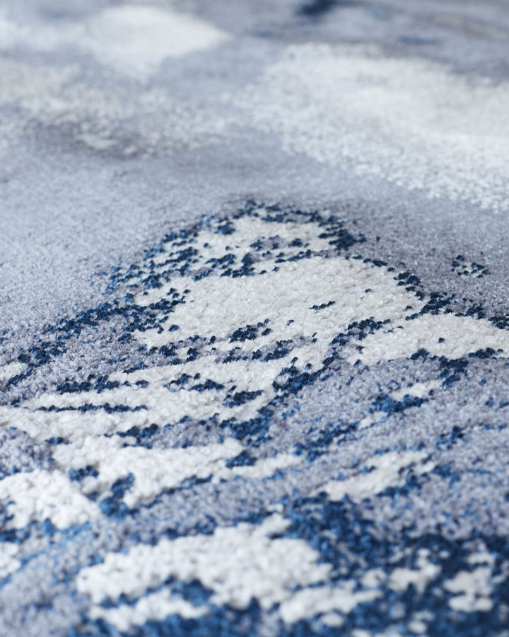 Close-up of a contemporary rug with blue and grey abstract pattern. Soft, textured weave with a shallow depth of field.