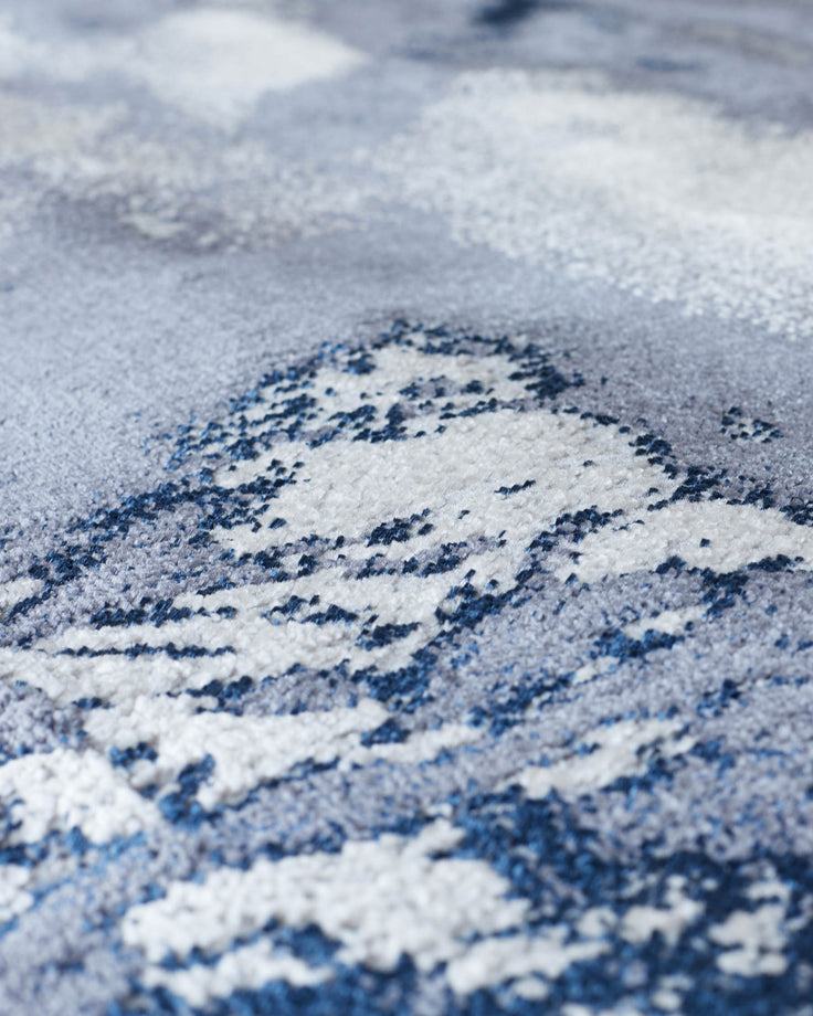 Close-up of a contemporary rug with blue and grey abstract pattern. Soft, textured weave with a shallow depth of field.